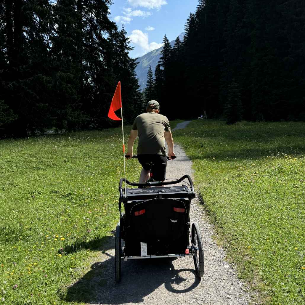 Person riding a bicycle with a bike trailer along a path