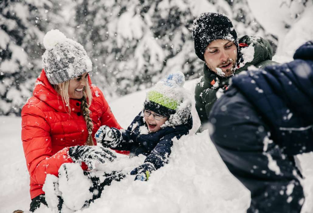 Winterspaß für die ganze Familie Familie mit zwei Kinder tobt gut gelaunt im Schnee