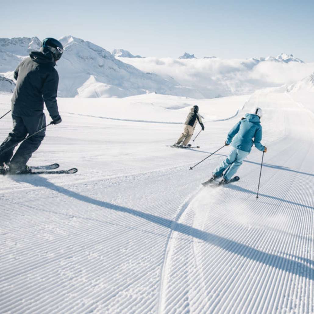 Skifahren für jedes Level Drei Personen fahren die Skipiste hinab